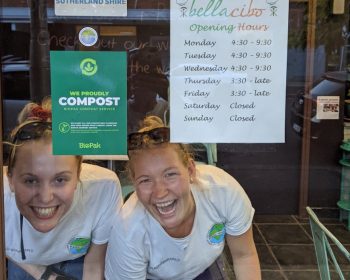 An image of two women in the window of Bella Cibo cafe with sustainable practices certificates